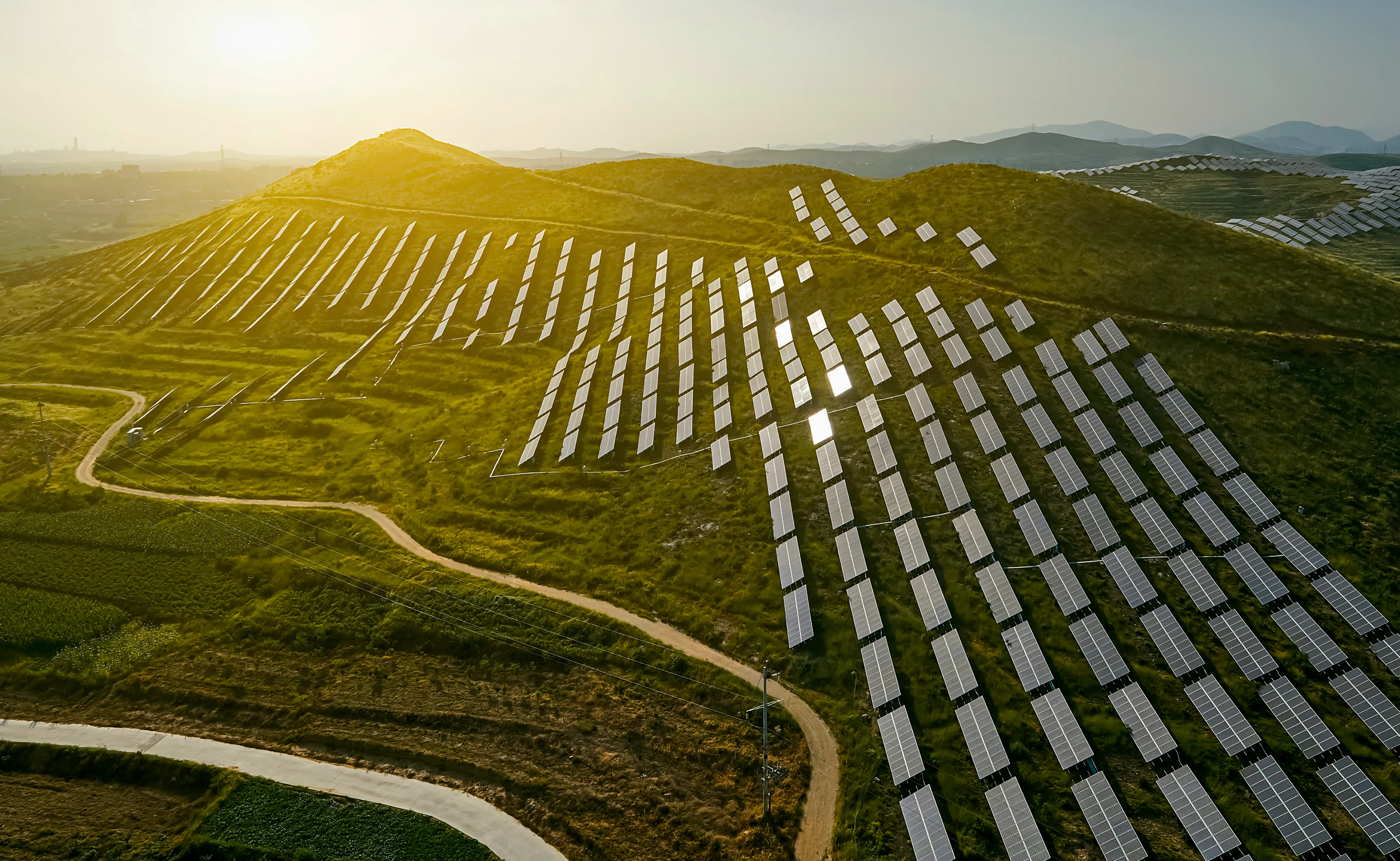 Solar arrays across rolling hills at sunrise